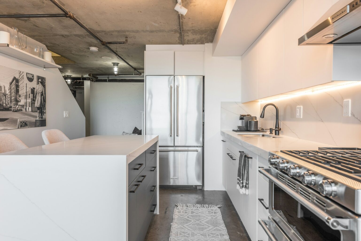 Reforma de cocina moderna con isla en Castellón. Muebles lacados, encimera de cuarzo y electrodomésticos integrados. Empresa de reformas con 10 años de experiencia